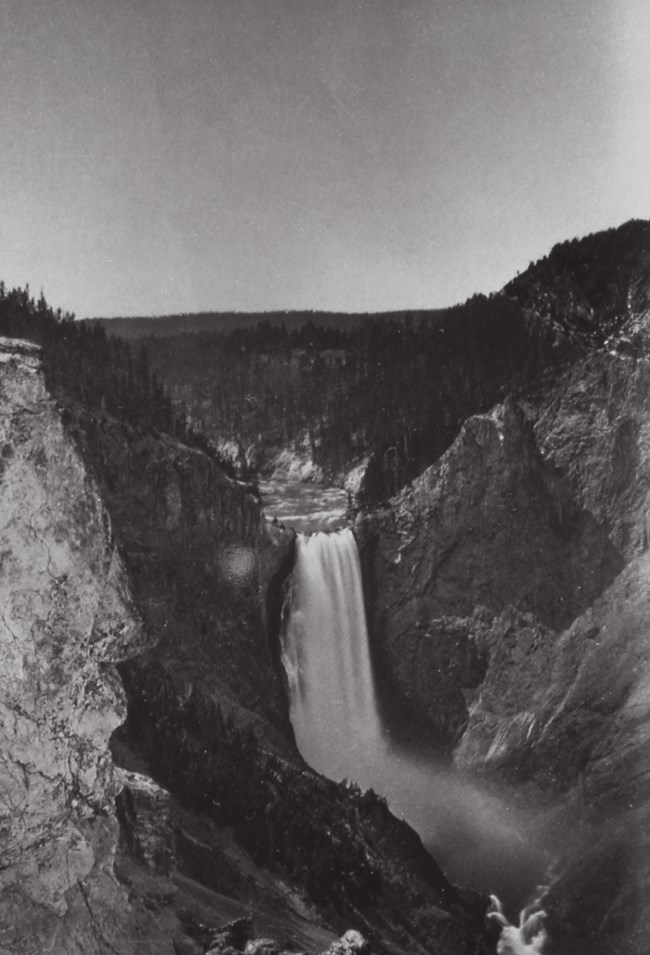 Yellowstone falls, as captured by William Henry Jackson. Black and white image of a large waterfall.