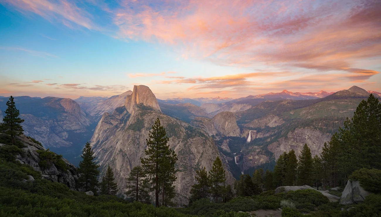 Yosemite sunset Picturesque view of Yosemite’s mountains and trees under a pink sunset.