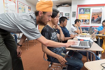 a park ranger helps a student using a laptop