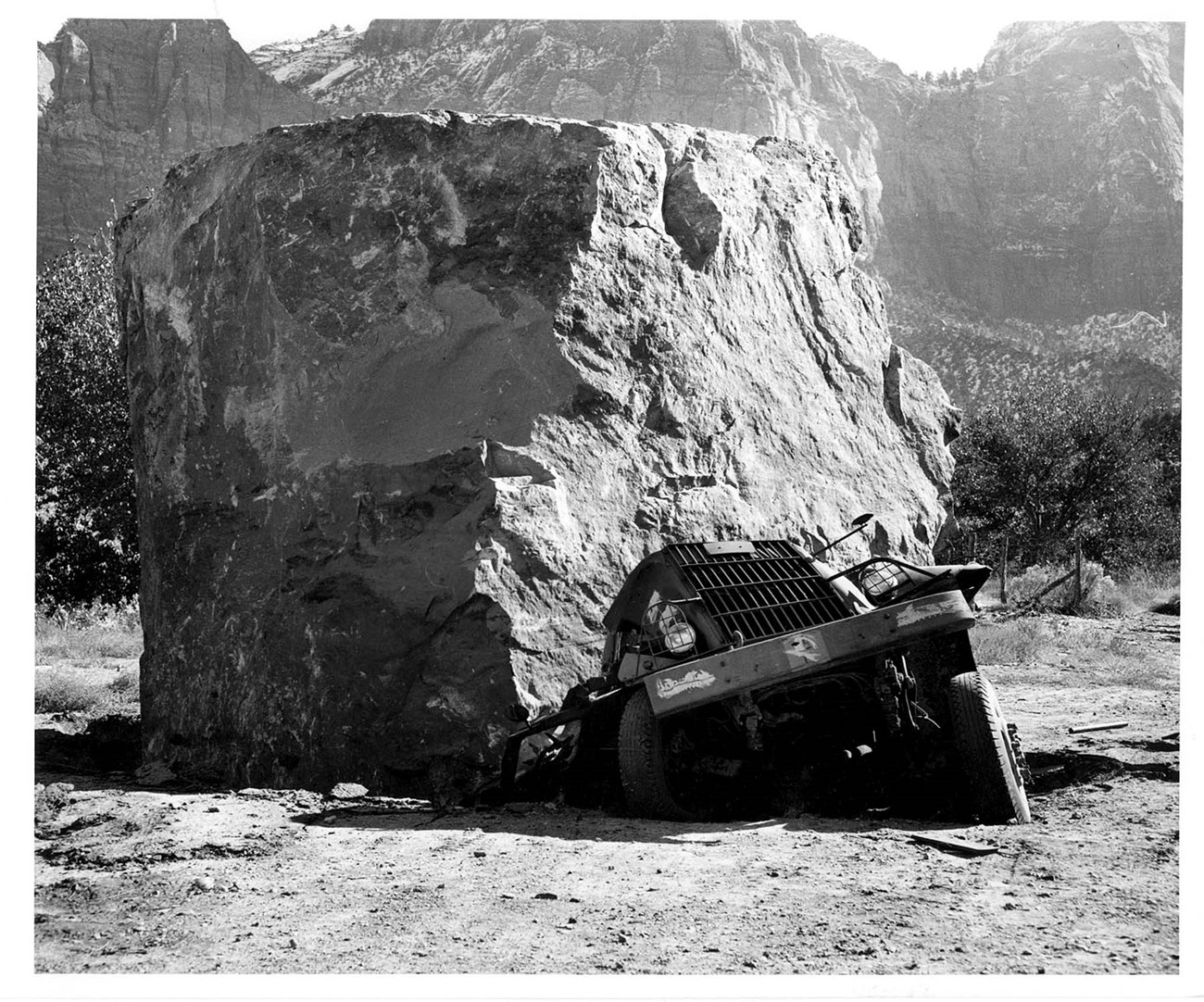 large boulder on top on smashed truck