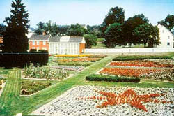 Colorful flower gardens with a brick building in the background.