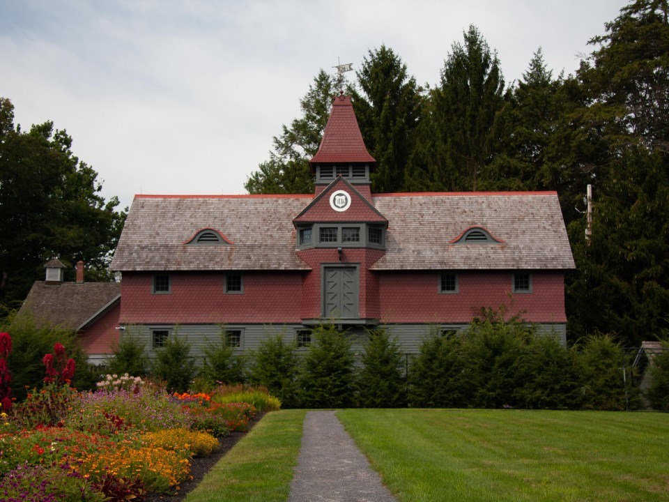 A wood clapboard and shingle building with cupola.