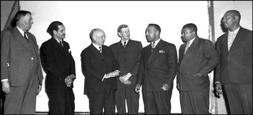 3 African American men in suits on the right stand next to a group of white men in suits 3 African American men in suits on the right stand next to a group of white men in suits