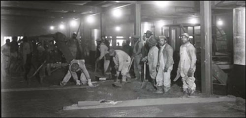 Pouring floor slab at K-25 african american workers in overalls inside building