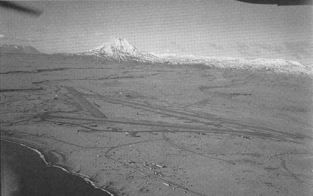 aerial view of a gravel air strip near a mountain on an island