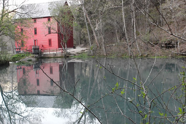 alley mill from the backside with red color on mill, spring pool blue in front of mill