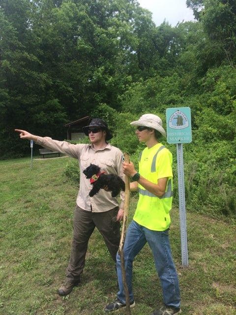 two adults with toy dog and Lewis and Clark trail sign