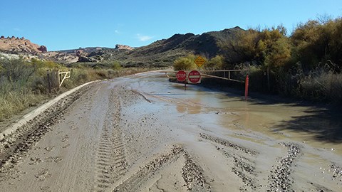 water and mud floods a road with a barricade