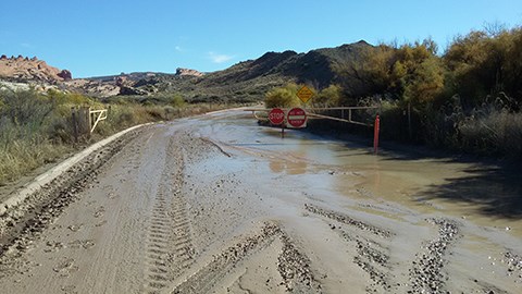 lt= water and mud floods a road with a barricade