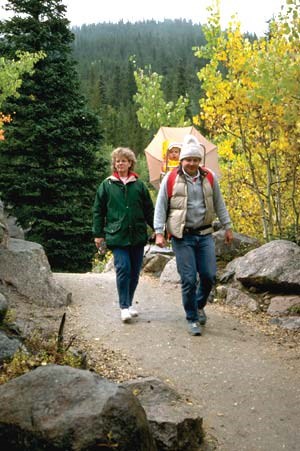 A family of three hikes on a trail.