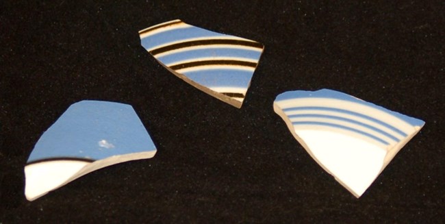 Photo of three fragments of bandedware with blue, black, and white colored bands.