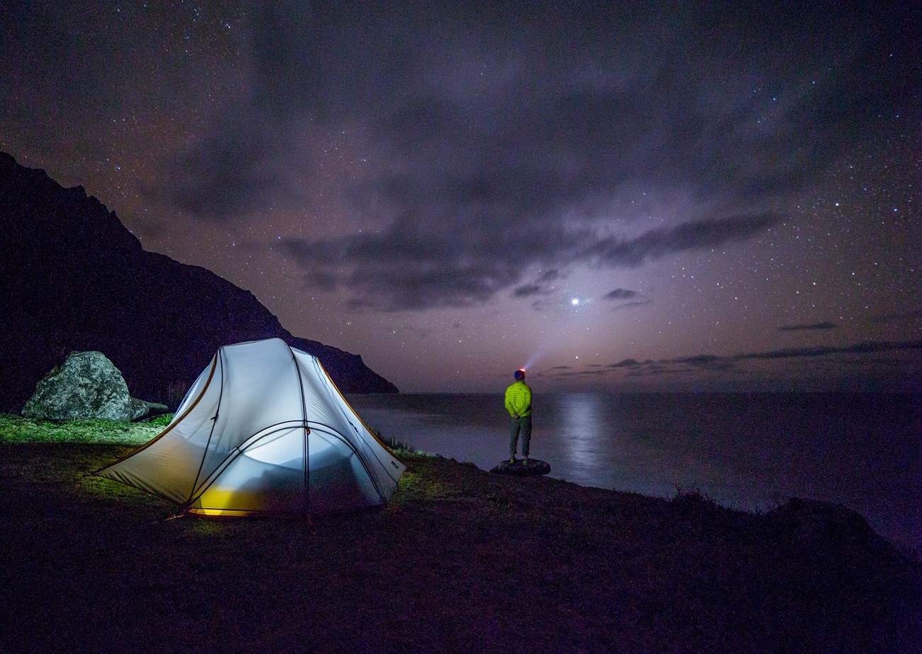 man camping at a lake at night