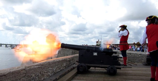 Iron cannon being fired on gun deck.