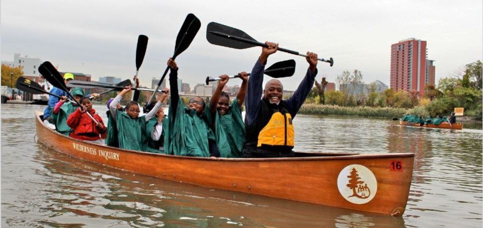 Man and students in canoe on urban river