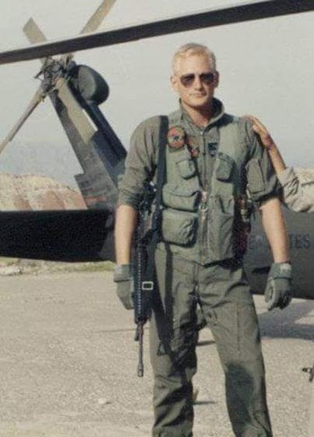 lt= Bill Bouley, in military uniform stands in front of a helicopter