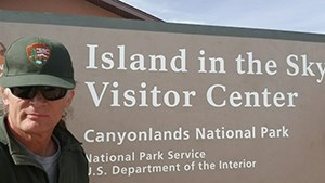 a ranger in front of a sign reading Island in the Sky Visitor Center Canyonlands National Park