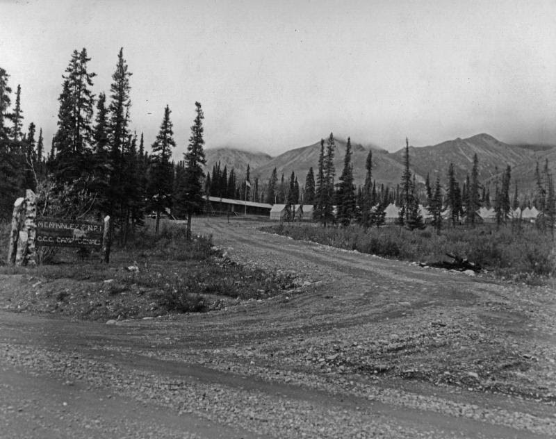 a dirt road leading up to a tent camp with numerous orderly tents