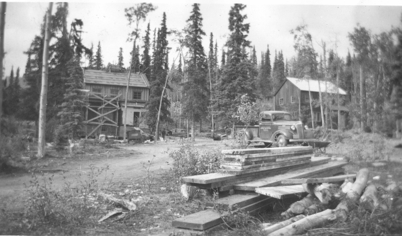 lumber near partially constructed buildings in a forest