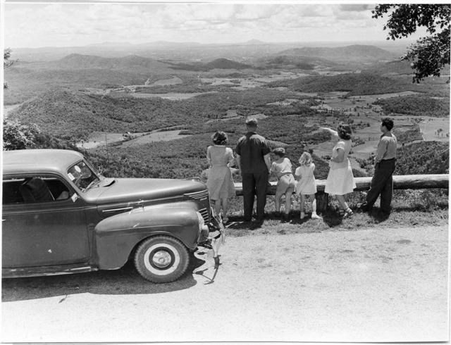 A family standing beside their car at an overlook. Taken in 1946.