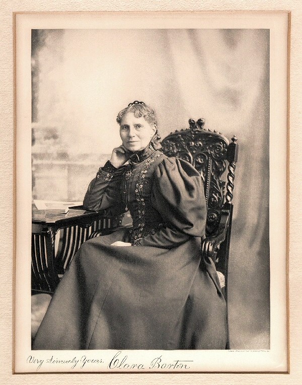 Clara Barton in 1897. Clara Barton sitting at her desk and looking at the camera