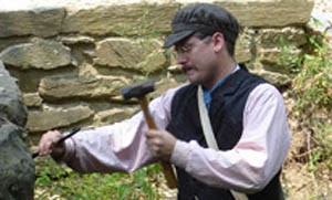 Stonemason in costume with hammer and chisel.