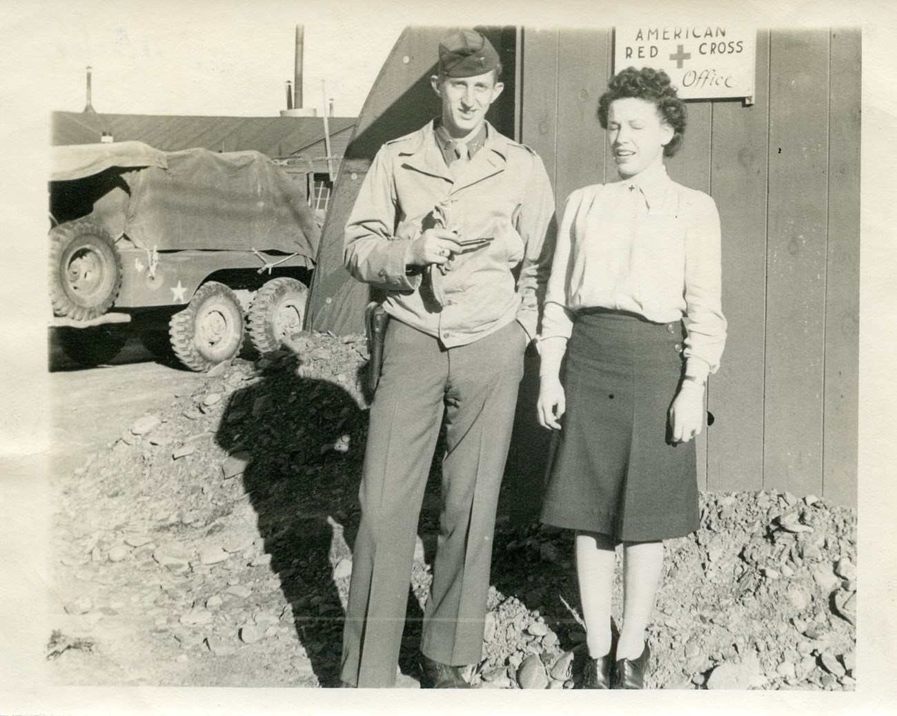condrills a woman and man in uniform pose outside a small military structure