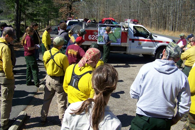 lt= Fire personnel gather for a morning briefing.