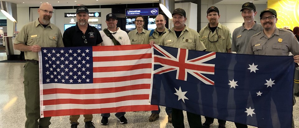 Interagency Partners en route to Australia A group of men and women hold US and Australian flags.