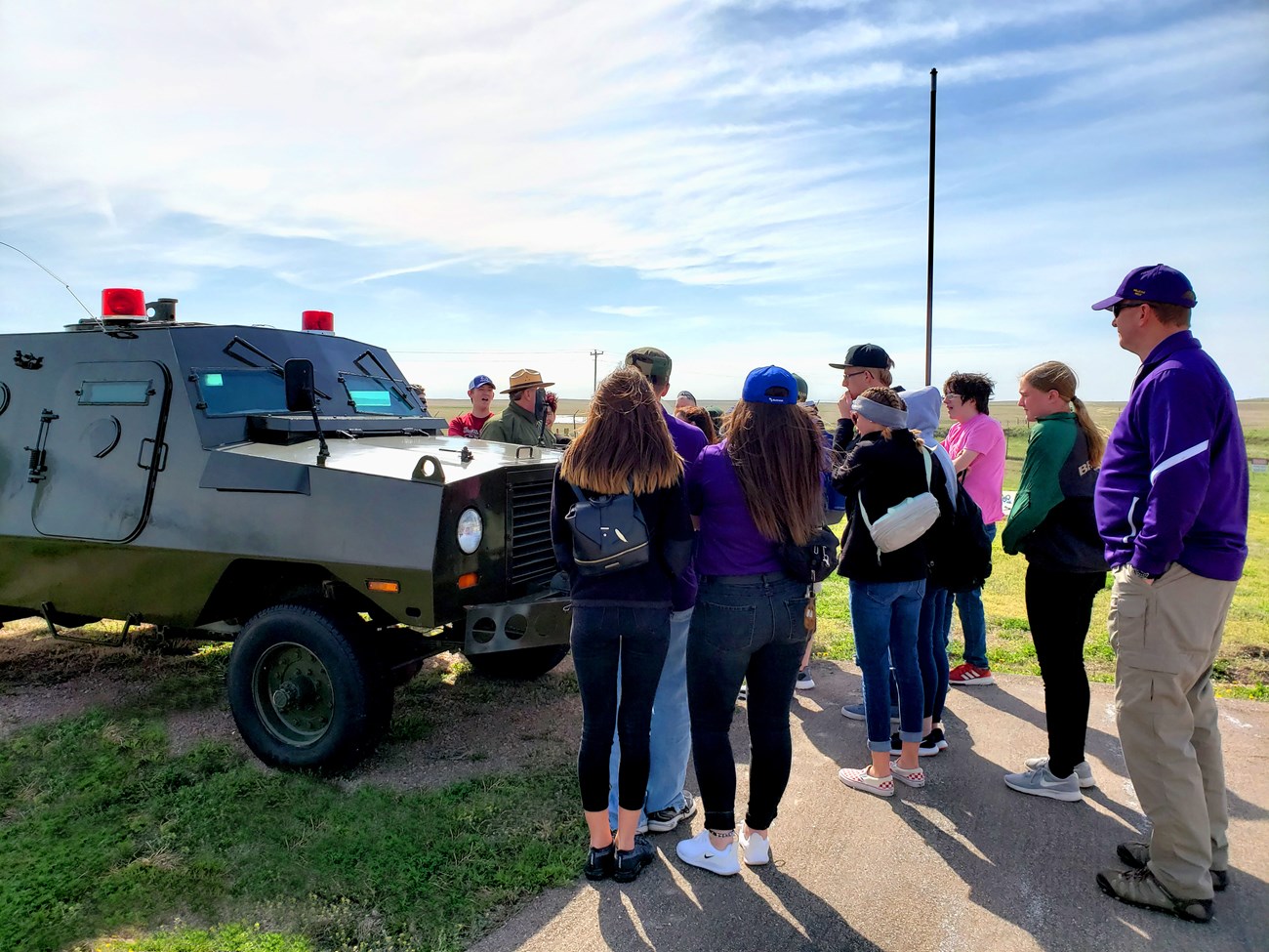 Students and a park ranger stand around an armored vehicle.