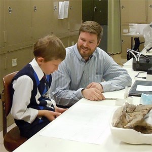 boy sitting with scientist in lab