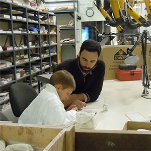 boy sitting with scientist in lab