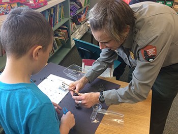 a park ranger assists a student in dissecting an owl pellet