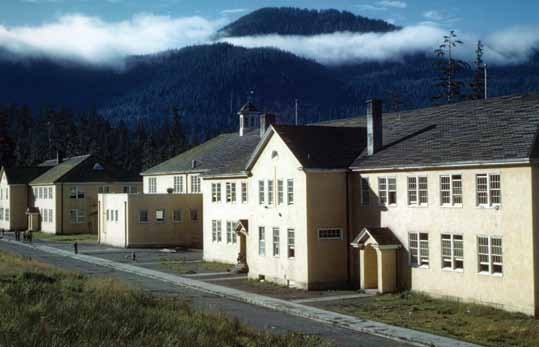 Color photograph of large yellow buildings with mountains in background