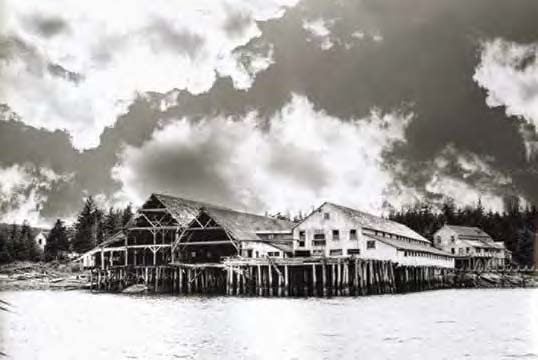 Black and white photo of large buildings on a wharf