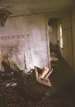 Modern photo of a dilapidated interior with large stove in the middle.