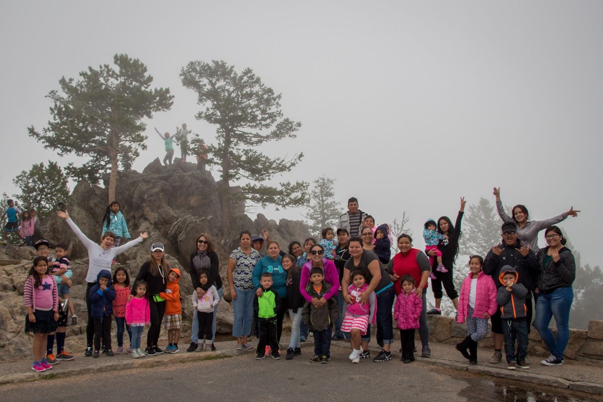 A group of young children and their families with a foggy mountain background A group of young children and their families with a foggy mountain background