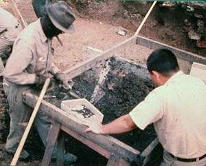[photo] Two archeologists sift soil, looking for archeological resources.