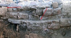 The south wall of the spring enclosure after excavation. The left arrow points to the outlet in the improved spring enclosure, the right arrow to the top of the old spring enclosure. Photograph courtesy of Emily J. Brown.