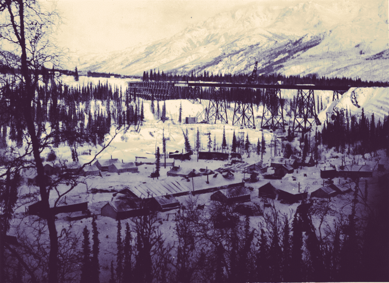 low buildings in a snowy forest near a railroad track