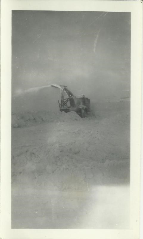 lt= Black and white photo of a large snow plow in a snow bank