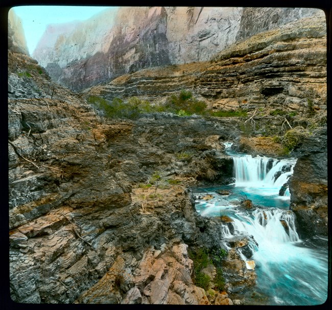 grca31879 Smaller waterfall landing in a large blue river.