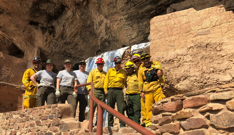 Photo of crew in front of wrapped cliff dwelling