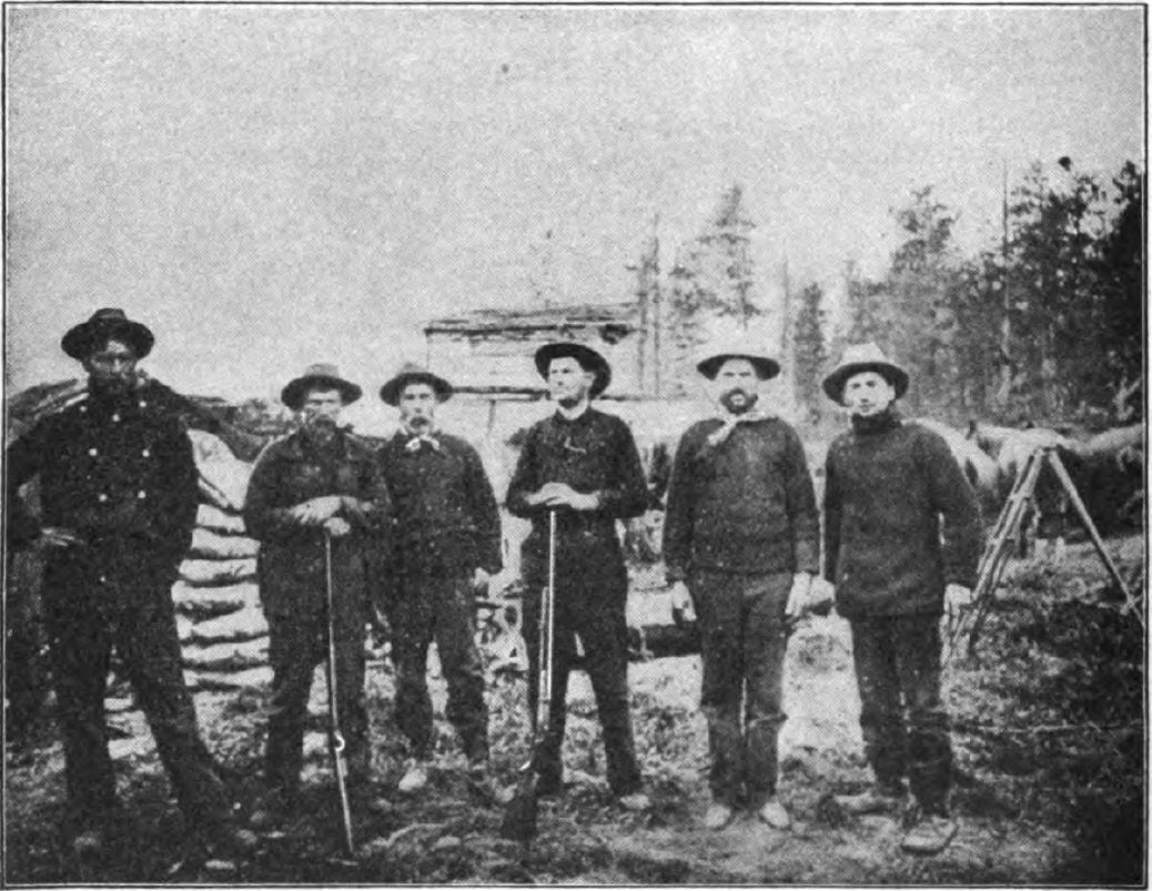herron 1 seven men standing near a half-built log cabin