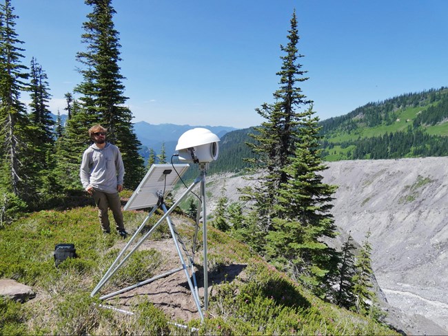 Person looking at the completed time-lapse camera installation along the Moraine Trail