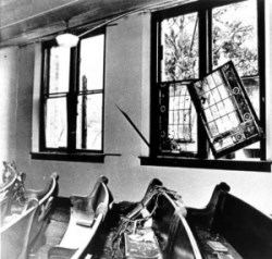 disarrayed pews inside a building near a window dislodged from its frame