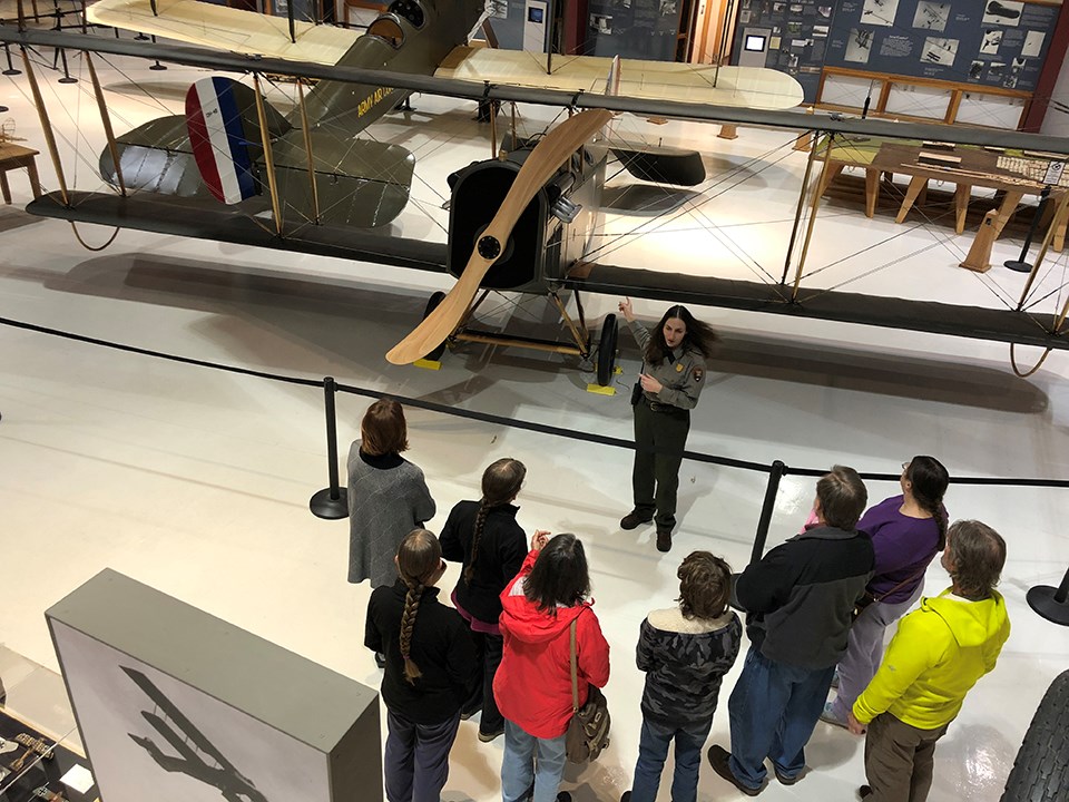 Photo of park ranger standing in front of the JN-4 Jenny inside Pearson Air Museum.