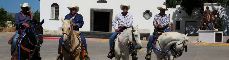 jinetes Four riders on horseback in front of a white church