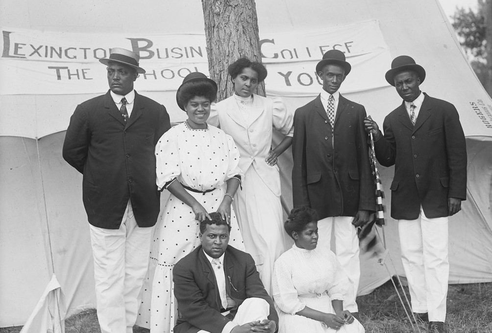 B&W photo of four African American men in black and three African American women in white.