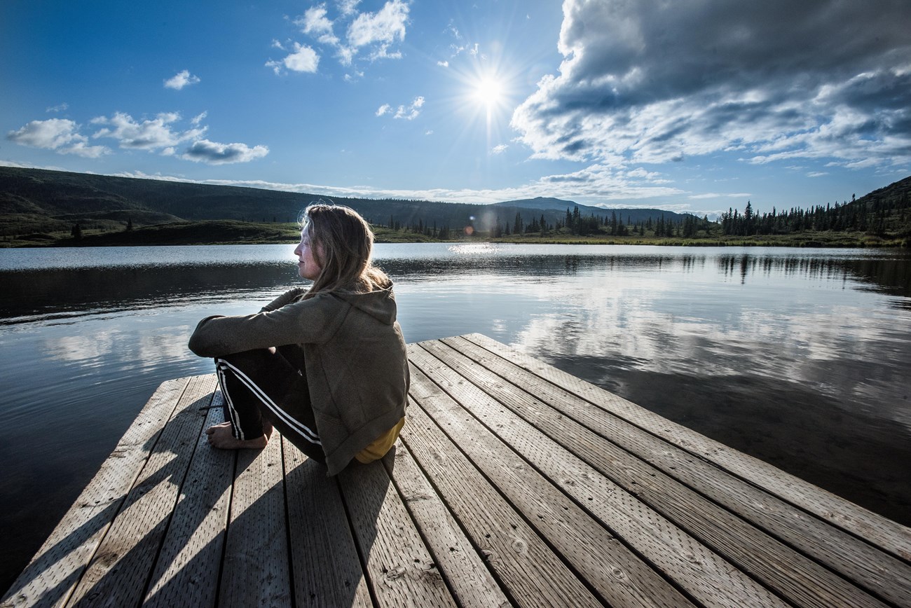 woman sits by lake