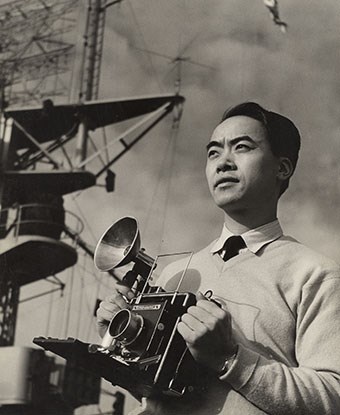 Chinese American man holding camera in front of ship